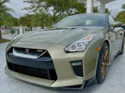 A technician applying a liquid ceramic coating to the hood of a luxury car.