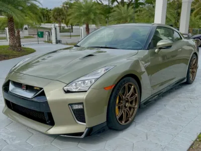 A technician applying a liquid ceramic coating to the hood of a luxury car.