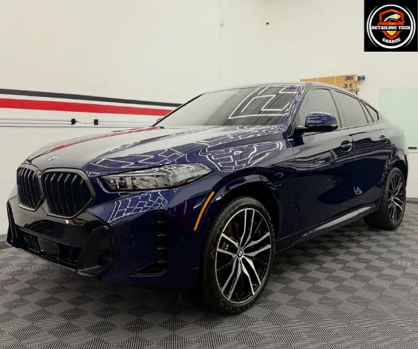 view of a luxury car parked inside a brightly lit detailing garage, showcasing a deep, high-gloss ceramic coating