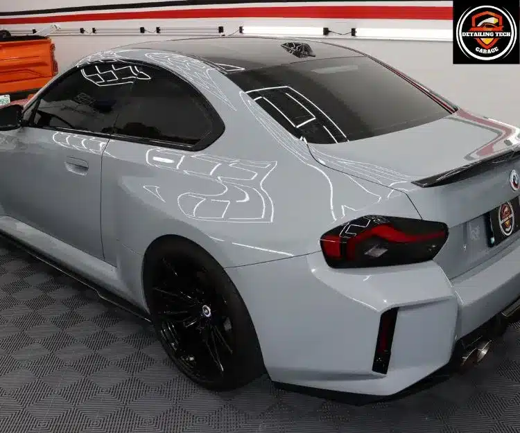 Rear three-quarter view of a light gray sports car with dark tinted windows and black wheels.